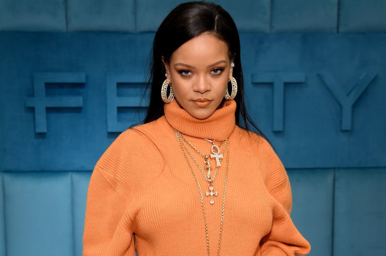 Rihanna posing in front of two pairs of shoes