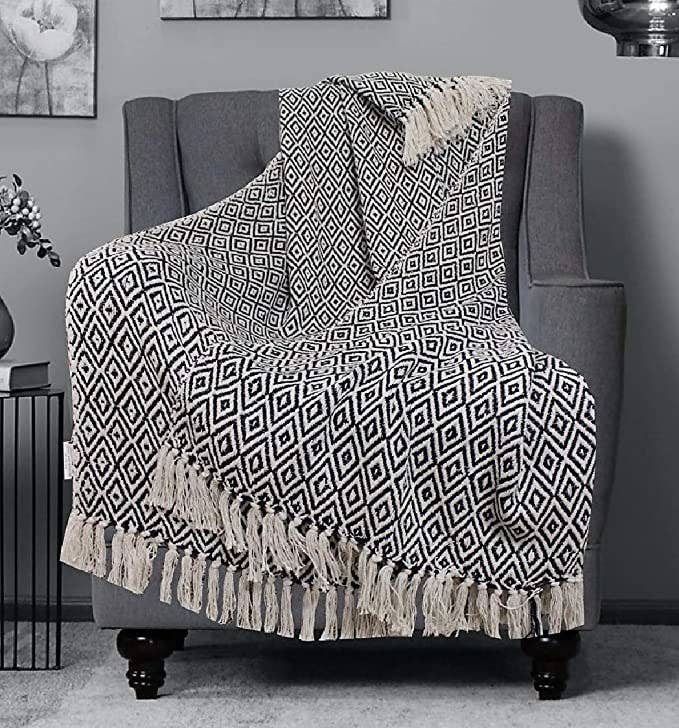 Monochrome geometric throw blanket with tassels at the ends.