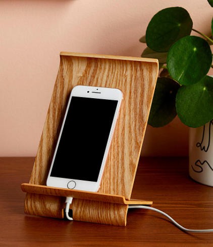A phone perched on the wooden dock with the charging cable coiled underneath