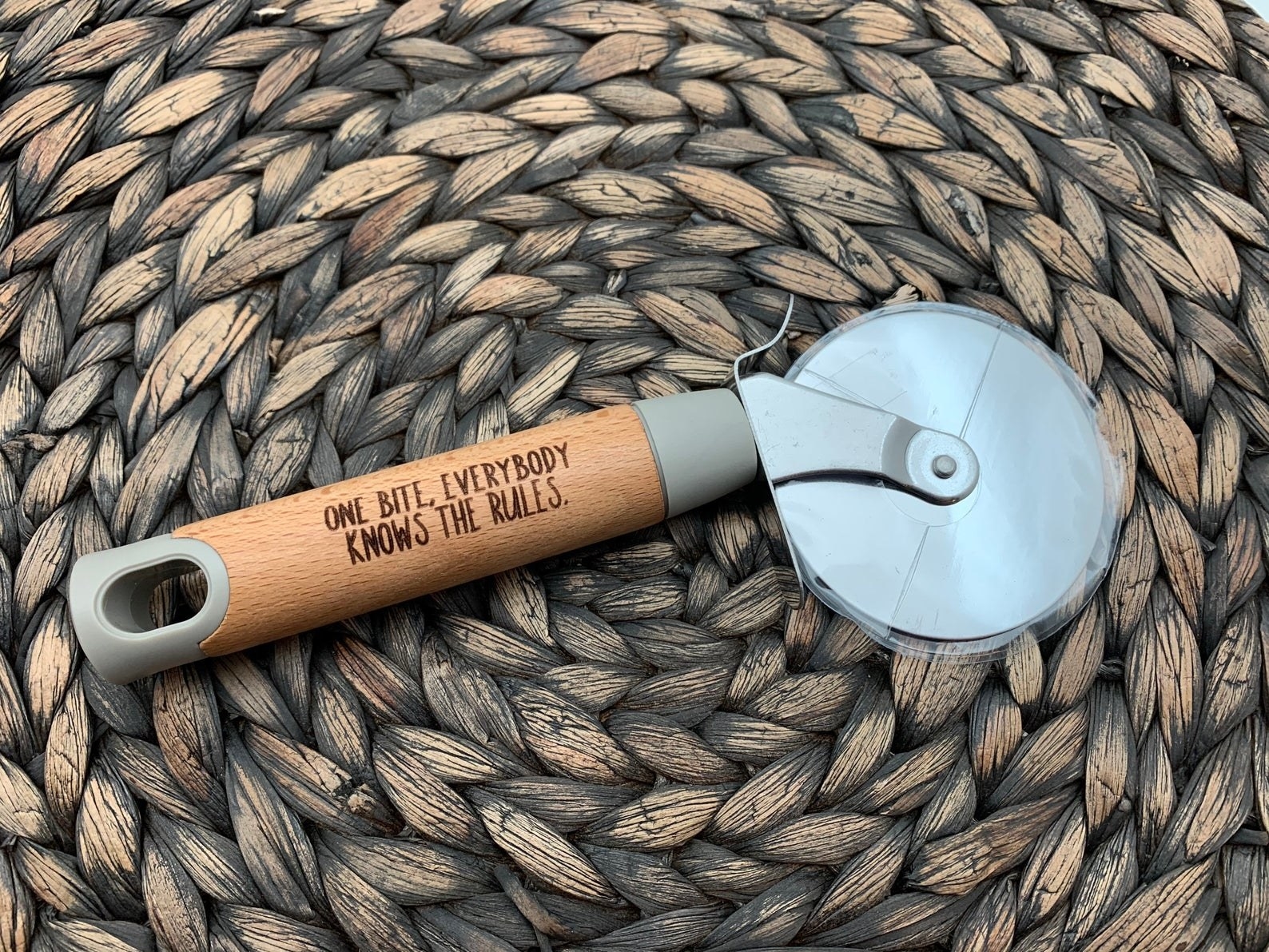 a pizza cutter with a wooden handle that says &quot;one bite, everybody knows the rules&quot;
