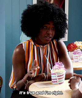 The Good Place character Simone Garnett in a striped shirt sitting at an ice cream shop table
