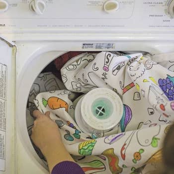 Person throwing colored tablecloth into washing machine