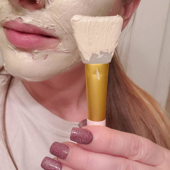 Reviewer holding spatula up to face with mask on it