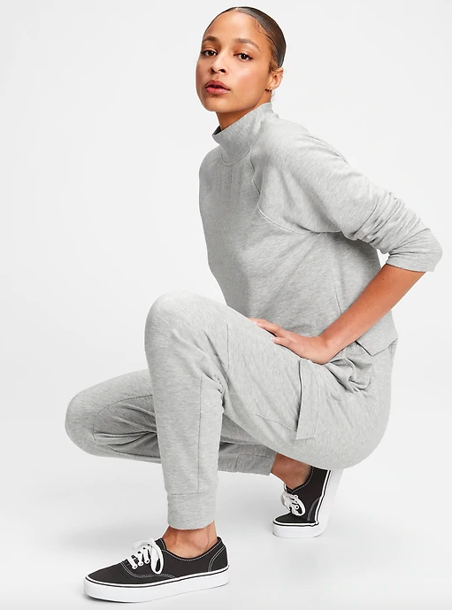 A person squatting down and wearing a long-sleeved shirt and joggers