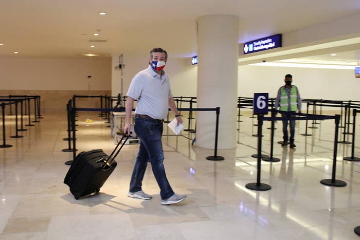 Ted Cruz wears a Texas flag mask as he pulls his luggage through Cancún International Airport