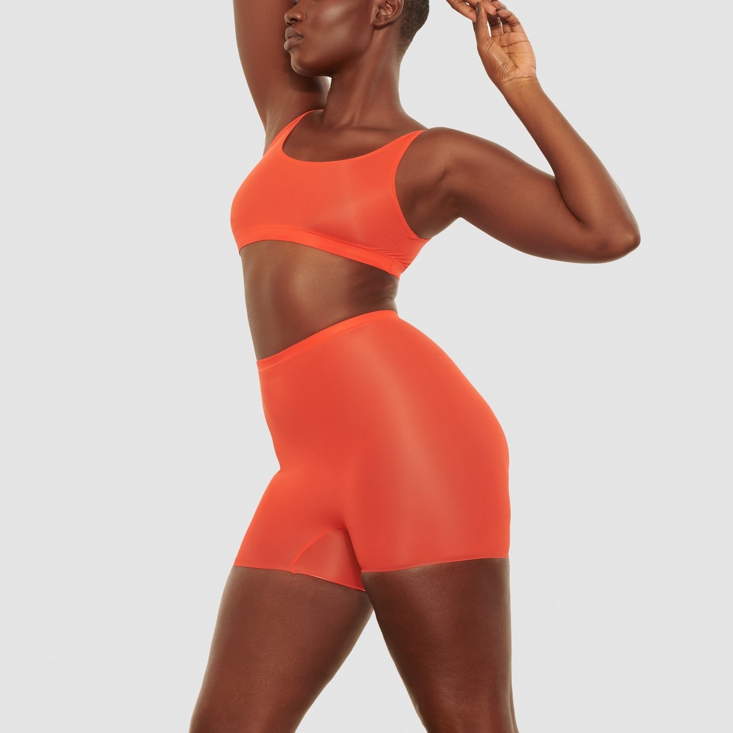 a model in an orange bralette and matching bike shorts