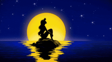 a gif of the little mermaid sitting on a rock with her hair blowing at night