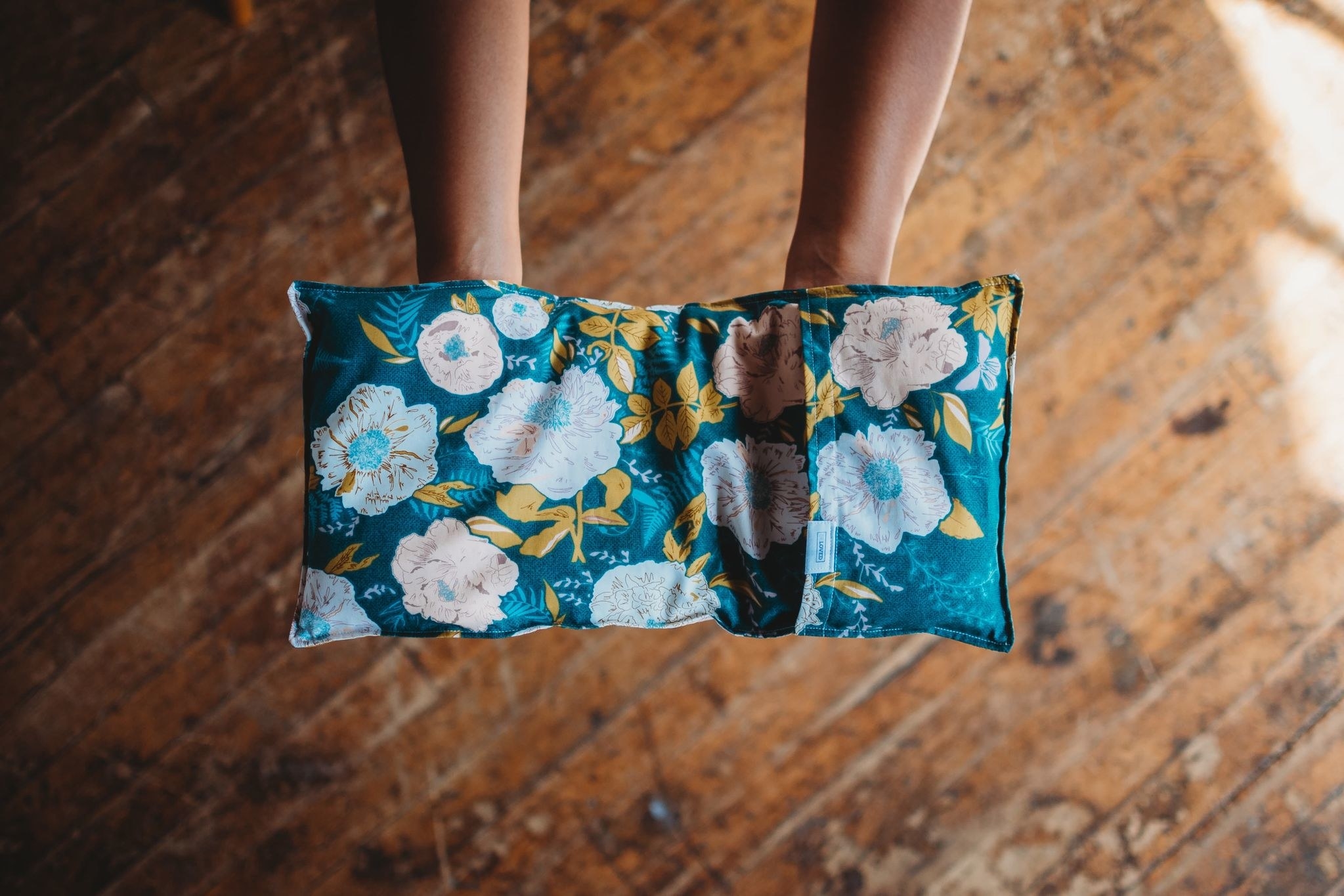 two hands holding the pack which has a blue floral case and is shaped like a rectangle