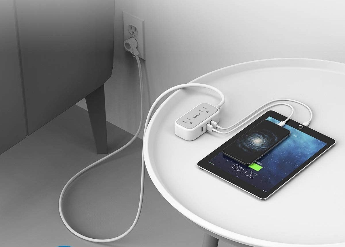 the power bar on a table with a tablet and a phone plugged in