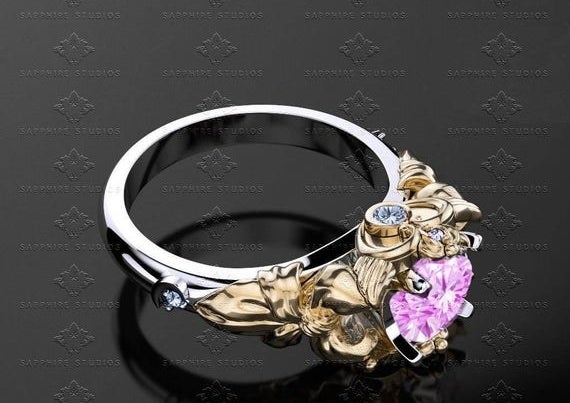A silver band with an etched gold setting and a pink saphire 