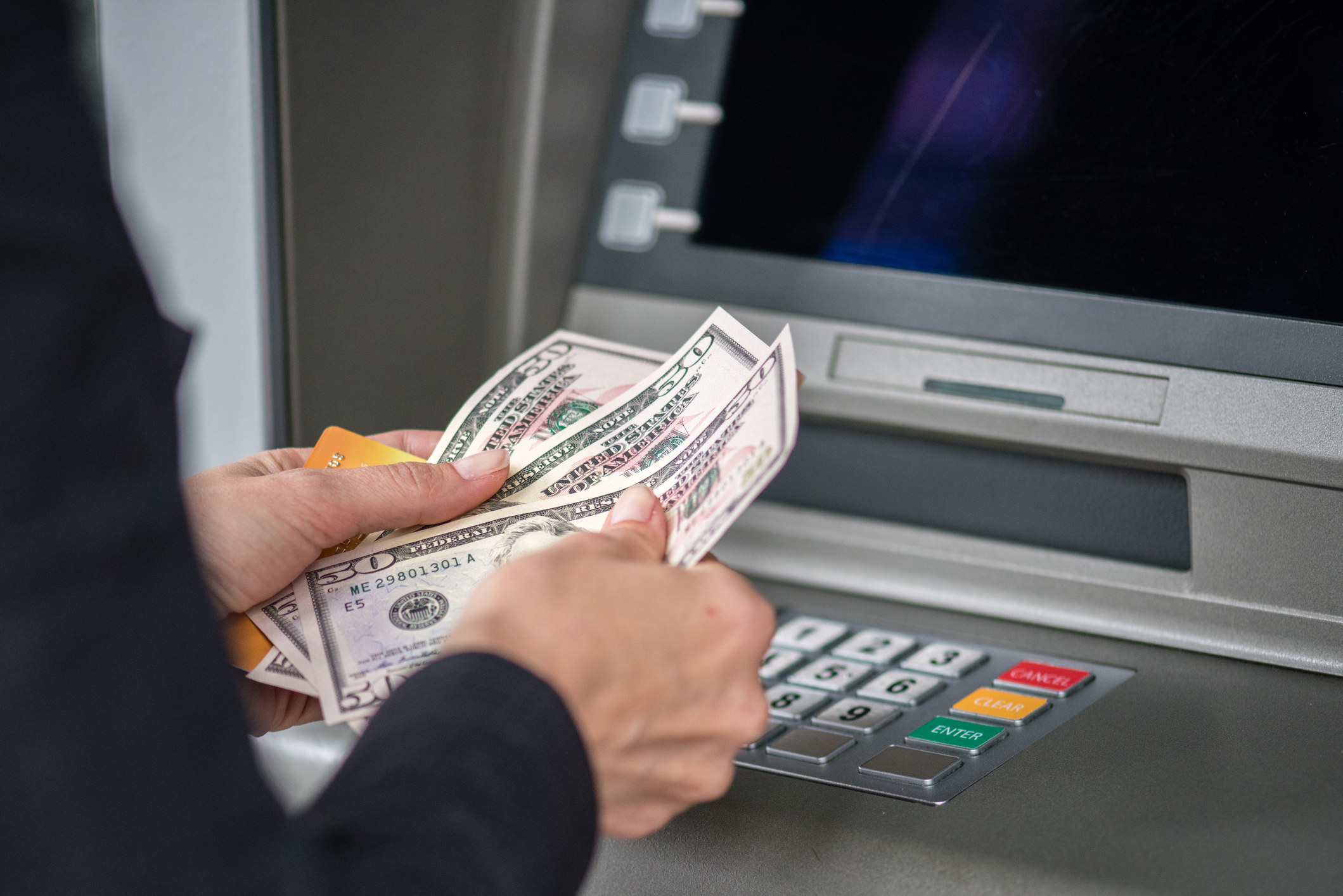 Woman counting cash at ATM