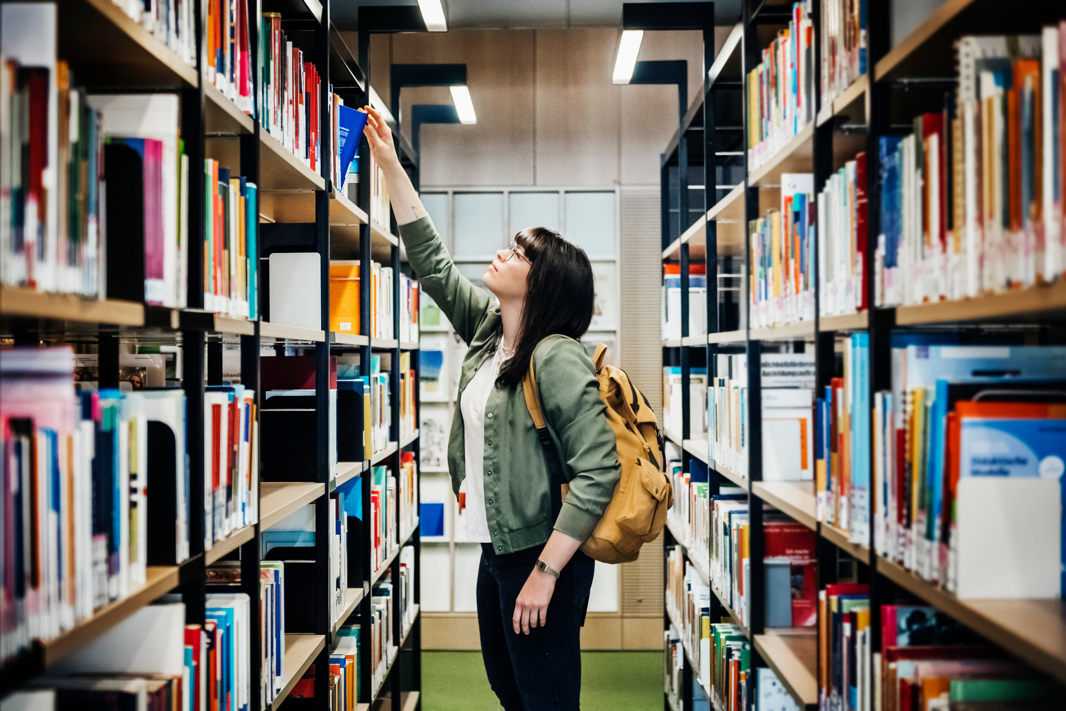 Student reaching for a book in the university library