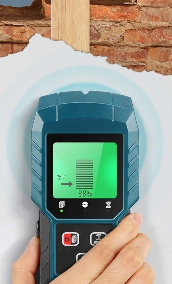 person finding wood in a wall with the stud finder