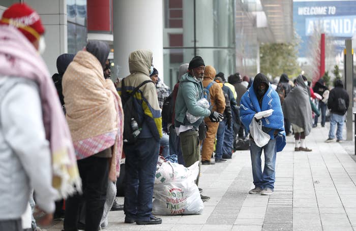 A line of more than 200 people, wearing beanies and hoodies and wrapped in blankets, outside a convention center