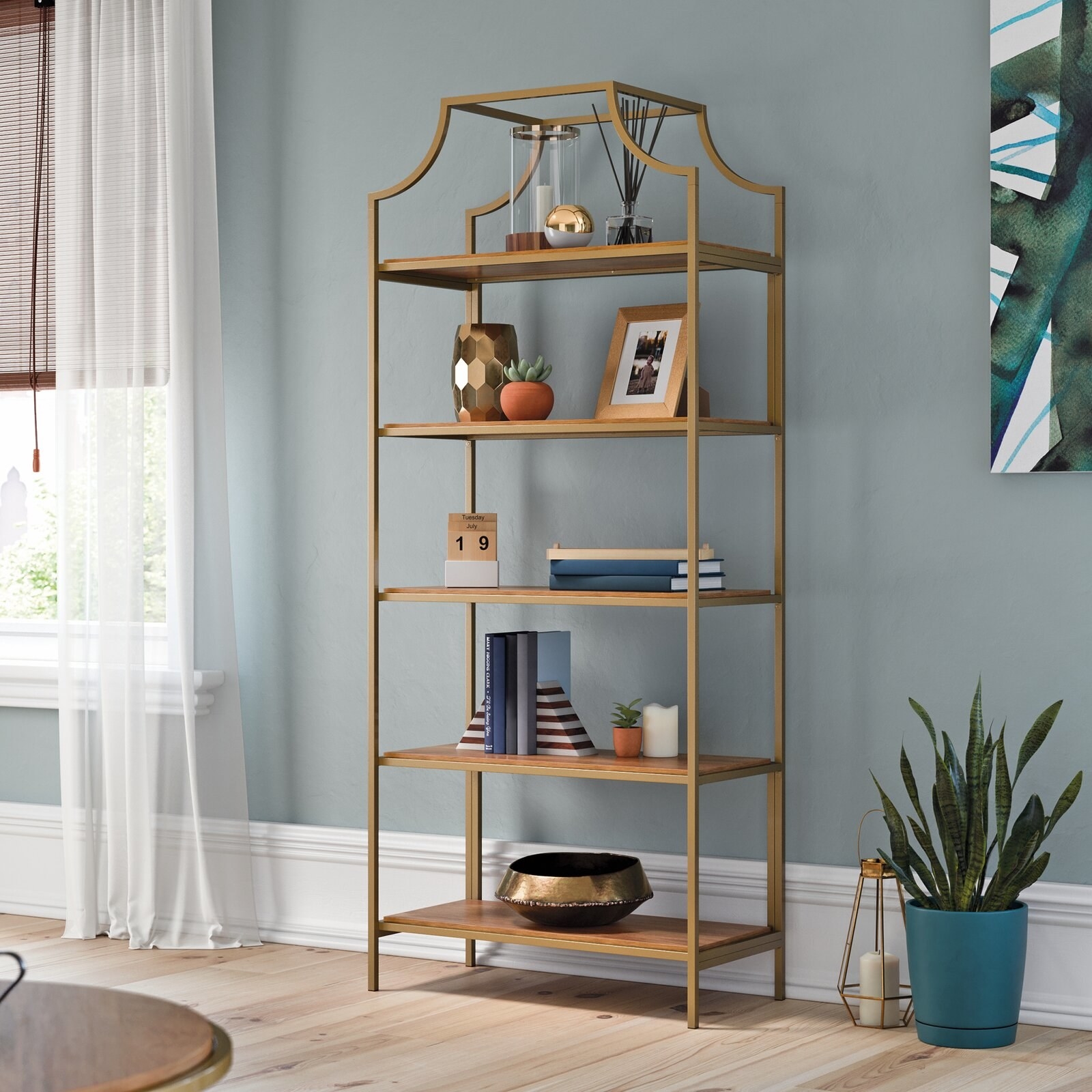 The bookshelf, which has five wooden shelves on an open metal frame, with an arched crown flourish on top