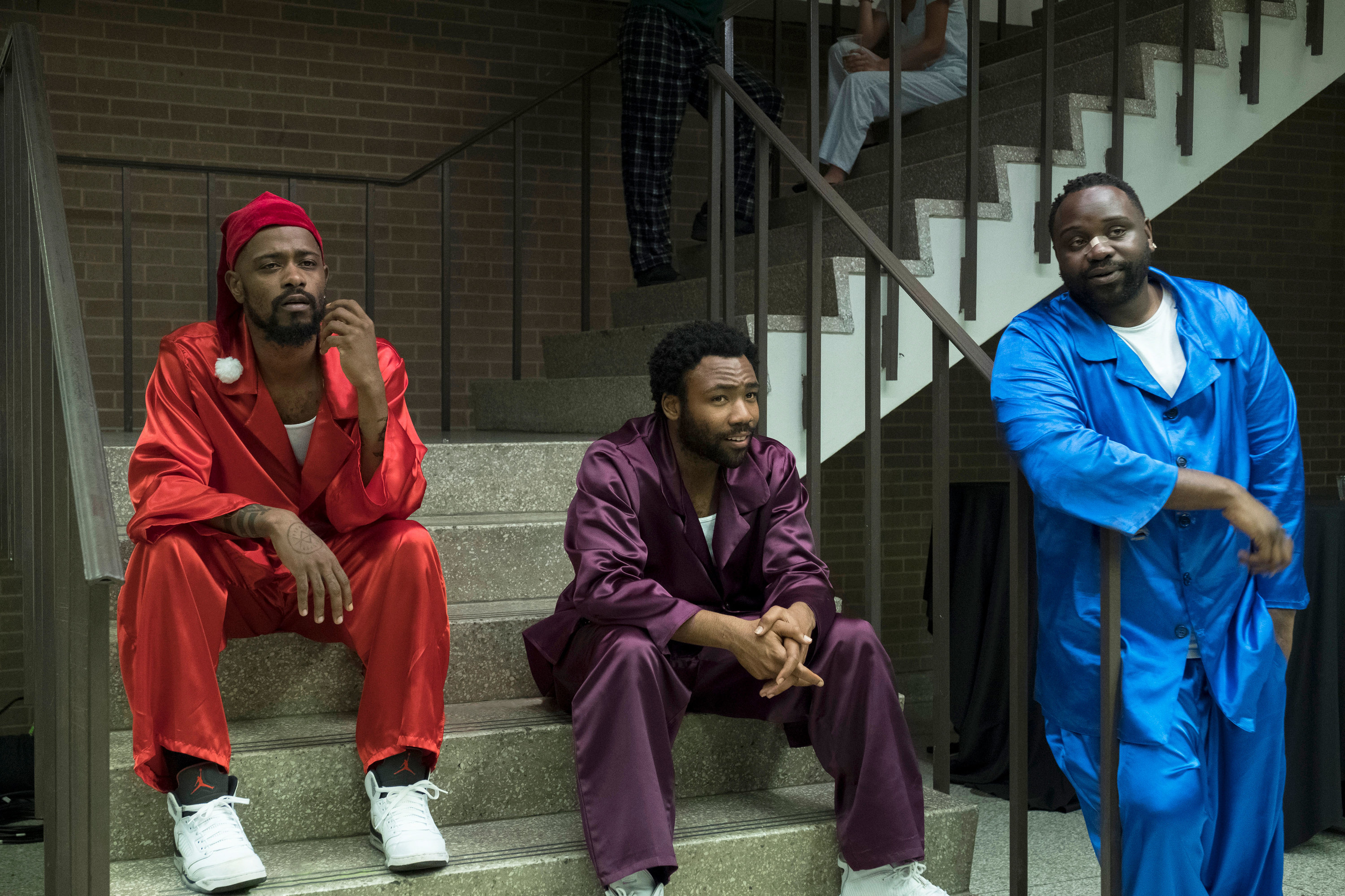 Lakeith Stanfield, Donald Glover, and Brian Tyree Henry sitting on steps in pajamas in the TV show Atlanta