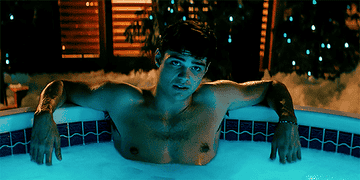 Peter Kavinsky smiling softly in a hot tub