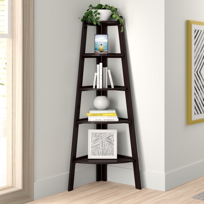 The bookcase, which fits in a corner and has three legs, with five shelves which start large at the bottom of the bookcase, and end up small at the top