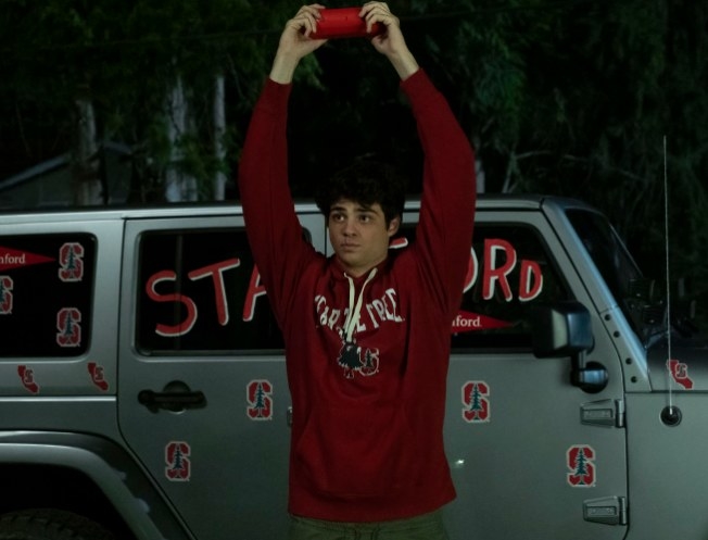 Peter standing in front of his car and holding a bluetooth speaker over his head 