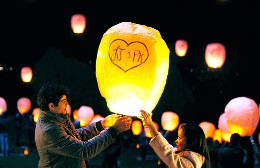 Pater and Lara Jean holding a lantern with &quot;LJ &amp; PK&quot; written on it in a heart