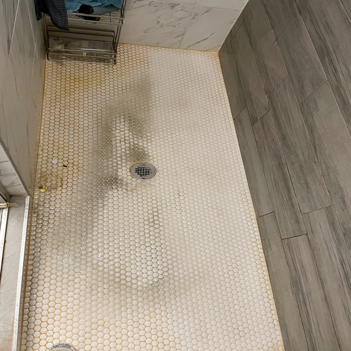 Reviewer's before picture of their dirty shower tiles 