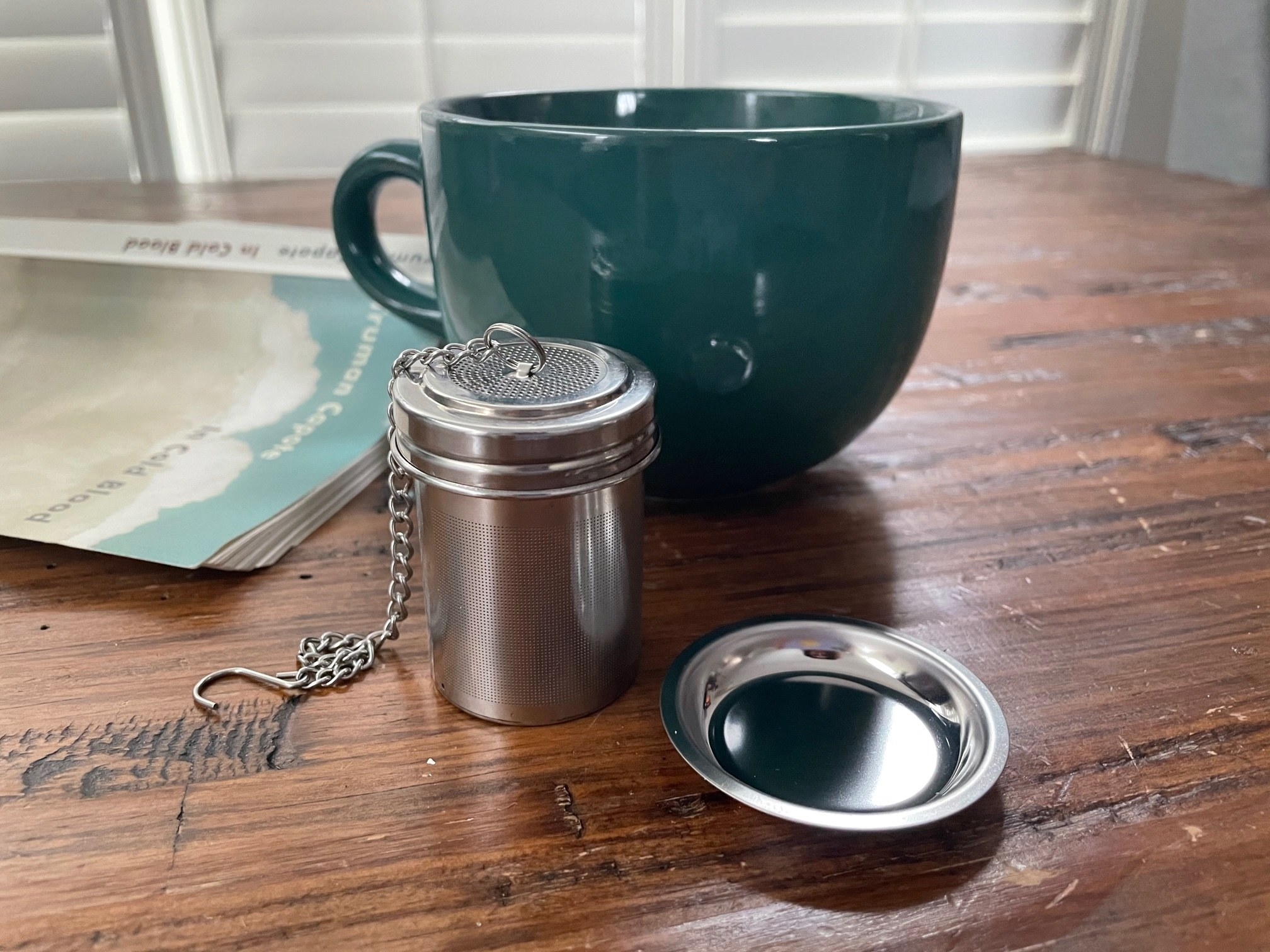 The tea strainer next to its plate and a mug 