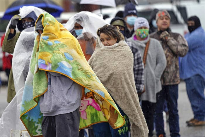 A line of people standing outside wrapped in blankets