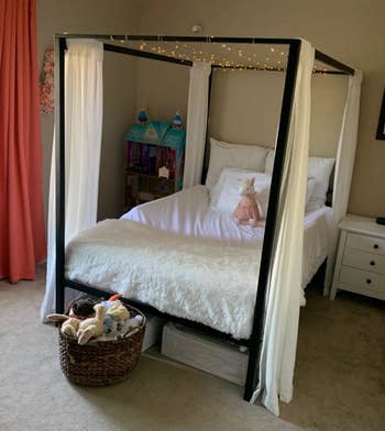 different reviewer's photo of the black bed frame with curtains and lights