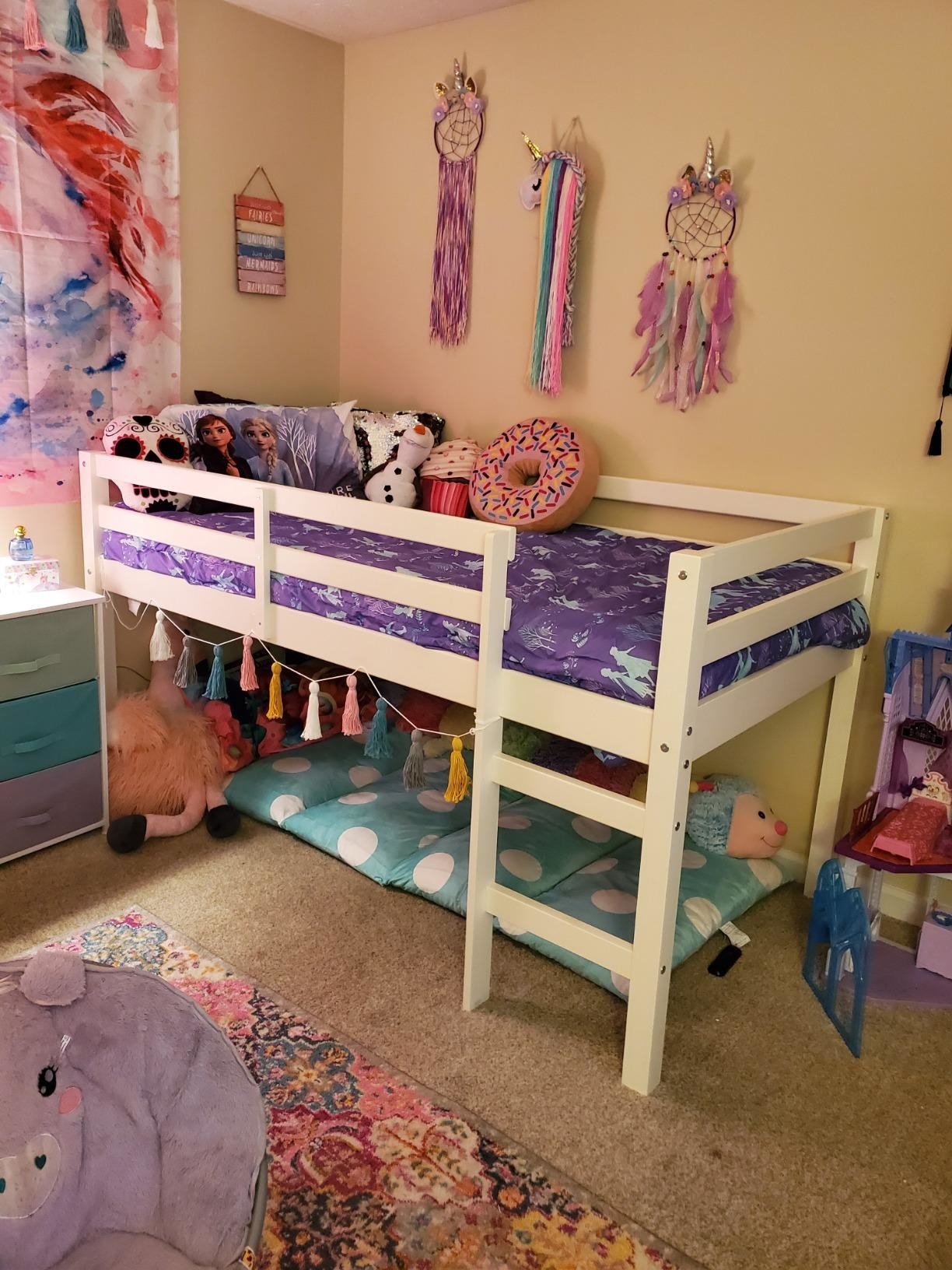 reviewer's photo of the lofted white bed frame with a play space underneath