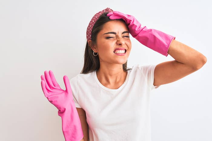 Woman wearing pink cleaning gloves grimacing.