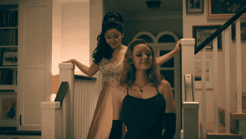 Lara Jean and Chris walking down the stairs in their prom dresses.