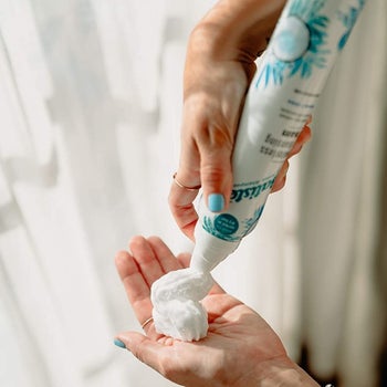 Model spraying dry shampoo foam into palm