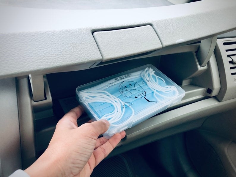 Model placing face mask storage case in glove compartment