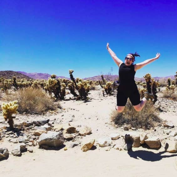 a customer reviewer jumping into the air while wearing the shorts in the desert