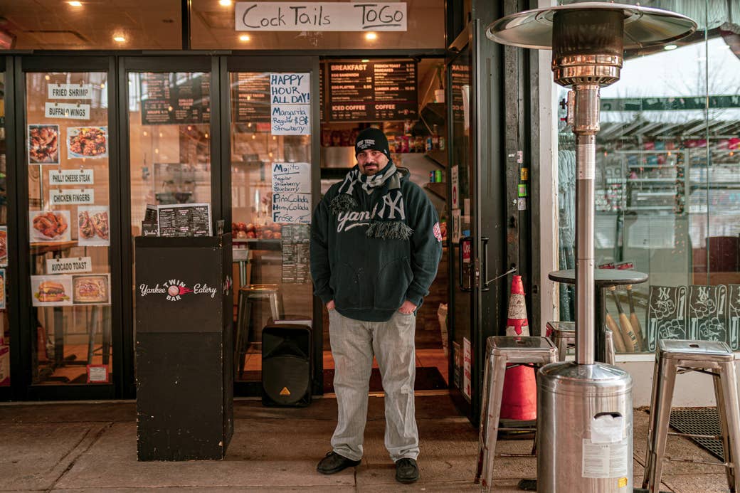 A man dressed in a Yankees sweatshirt, hat, and scarf