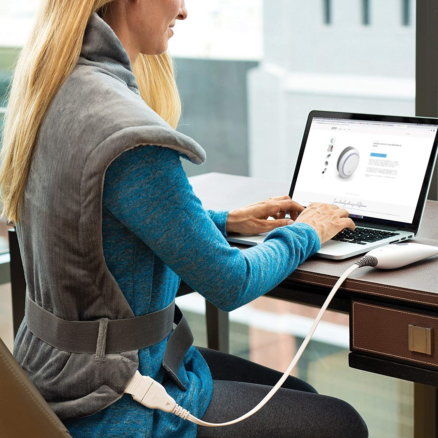 A person wearing the heating pad while working on their computer