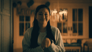Lara jean clutches her hands in joy while watching her dad propose