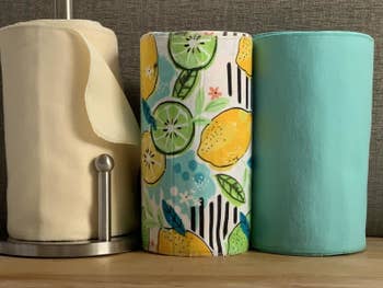 three rolls of the reusable cloths in beige, fruit print, and blue