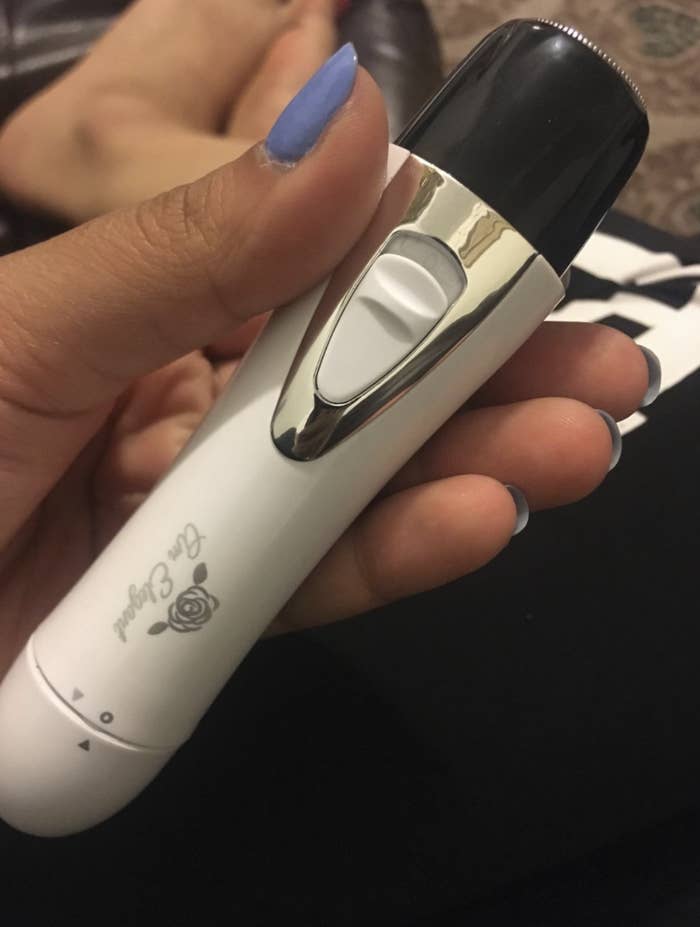 reviewer holding the razor which is shaped like a small cucumber