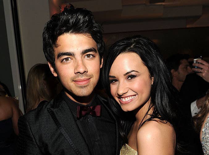 Joe Jonas and Demi Lovato posting at a press event 