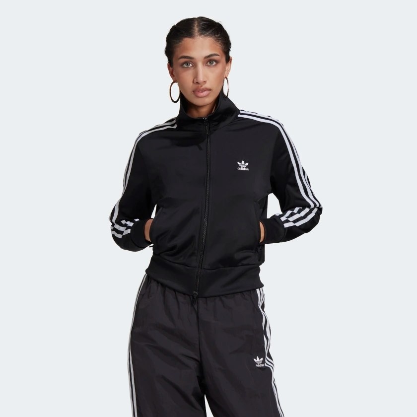 The black track jacket worn by a model, hands in pockets