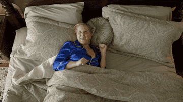 Amy Schumer stretching and smiling in bed 