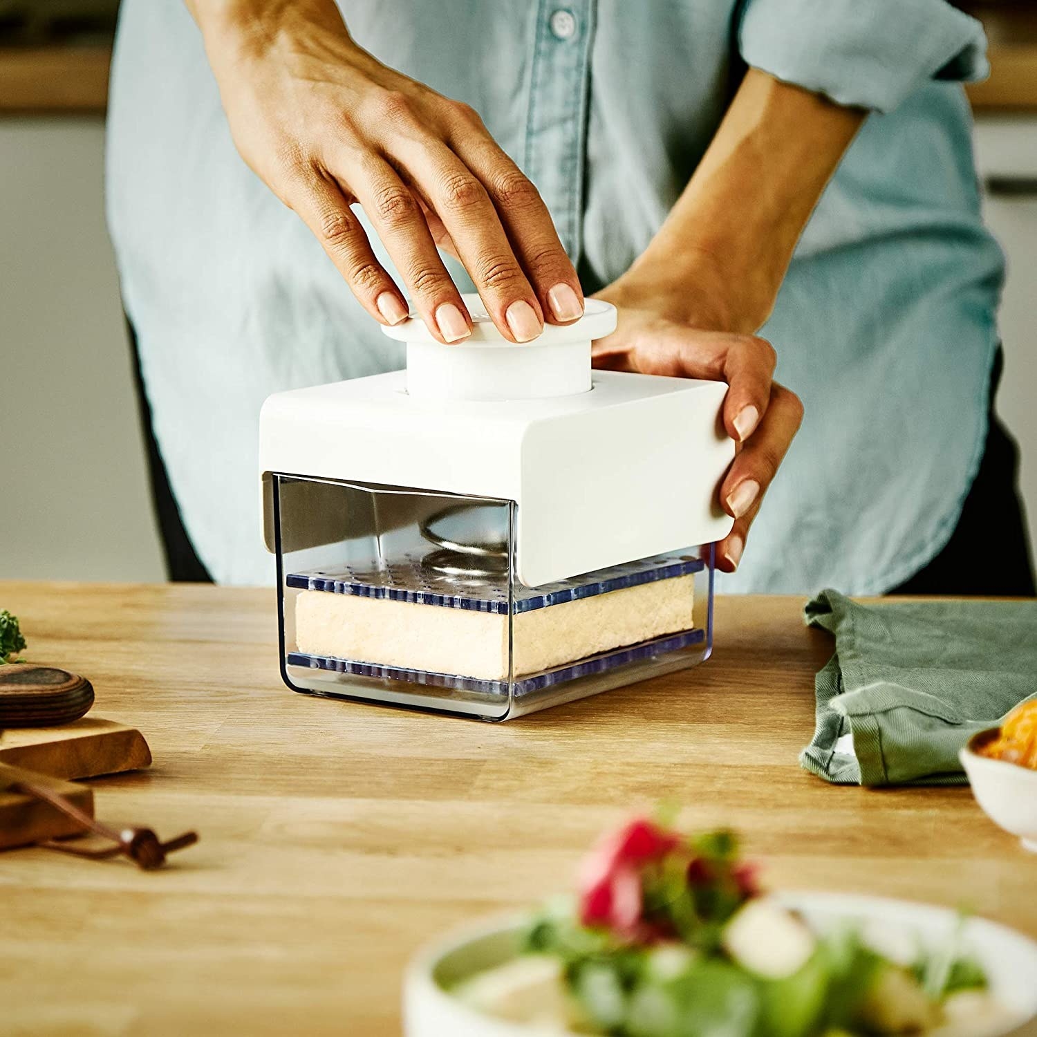 A person pressing tofu with the device