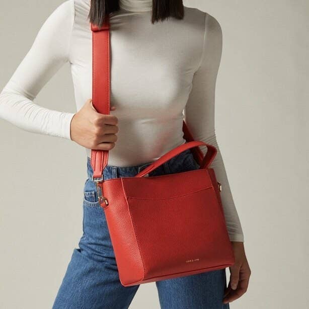 A person wearing a large purse with a wide strap across their chest