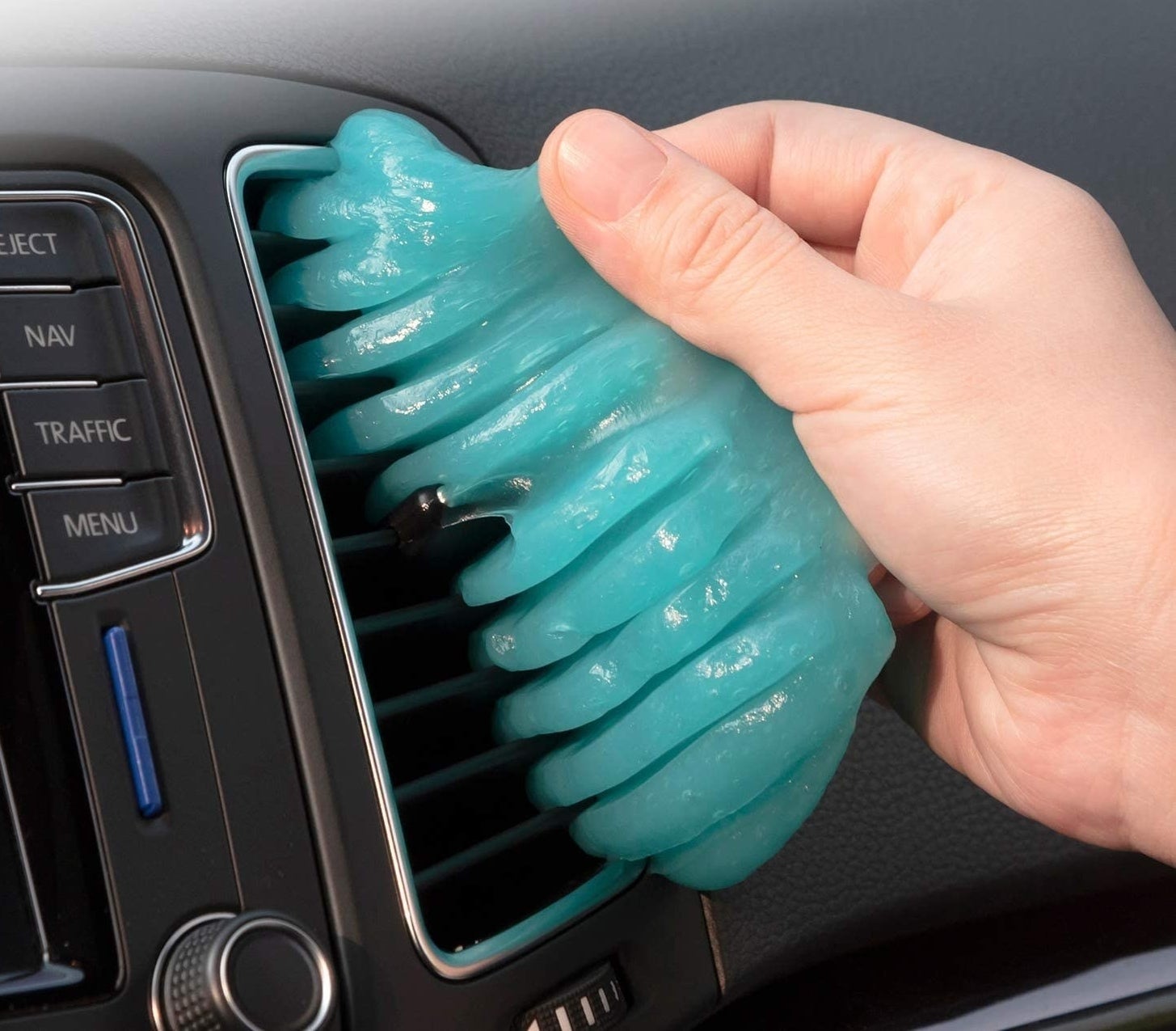 a hand pulls the cleaning putty out of a car vent