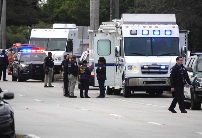 Law enforcement officers and vehicles on a road near the scene of the shooting