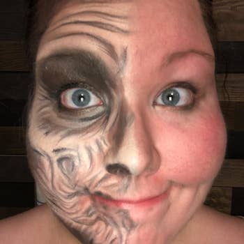A reviewer selfie showing the left side of their face covered in full elderly costume makeup, and the right side clear of makeup 