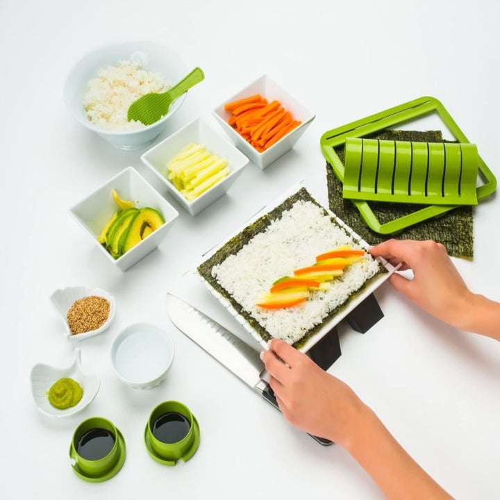 Hands prepare salmon and cucumber roll with DIY sushi making kit