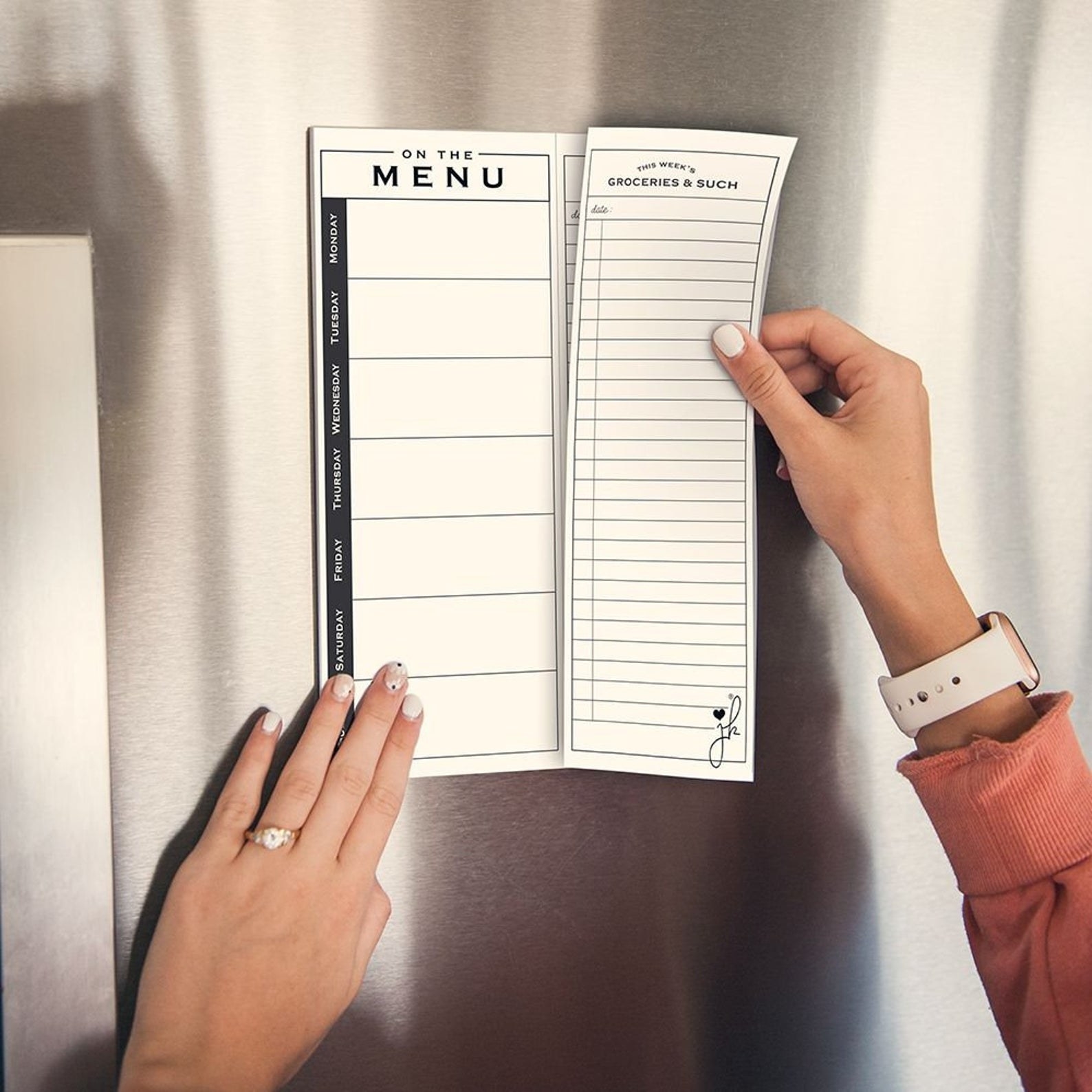 A hand tearing away one of the grocery list sheets