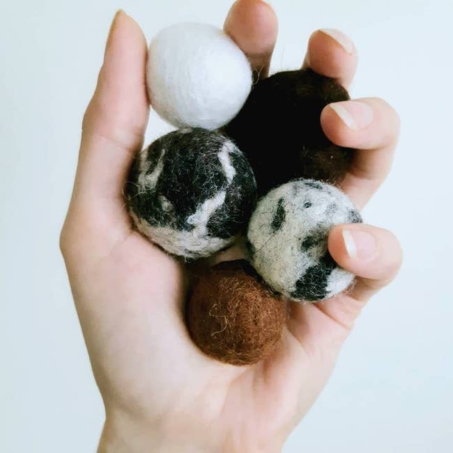 Person holding five felted wool balls in their hand 